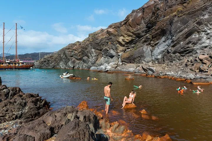 Trail across black lava on Nea Kameni on a Santorini volcano and hot springs boat tour, Santorini Greece