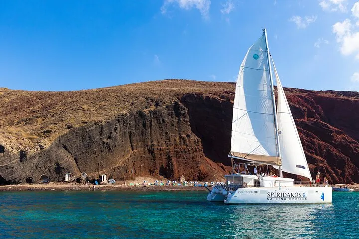 Private catamaran with an empty deck in a Santorini cove on a private catamaran cruise, Santorini Greece